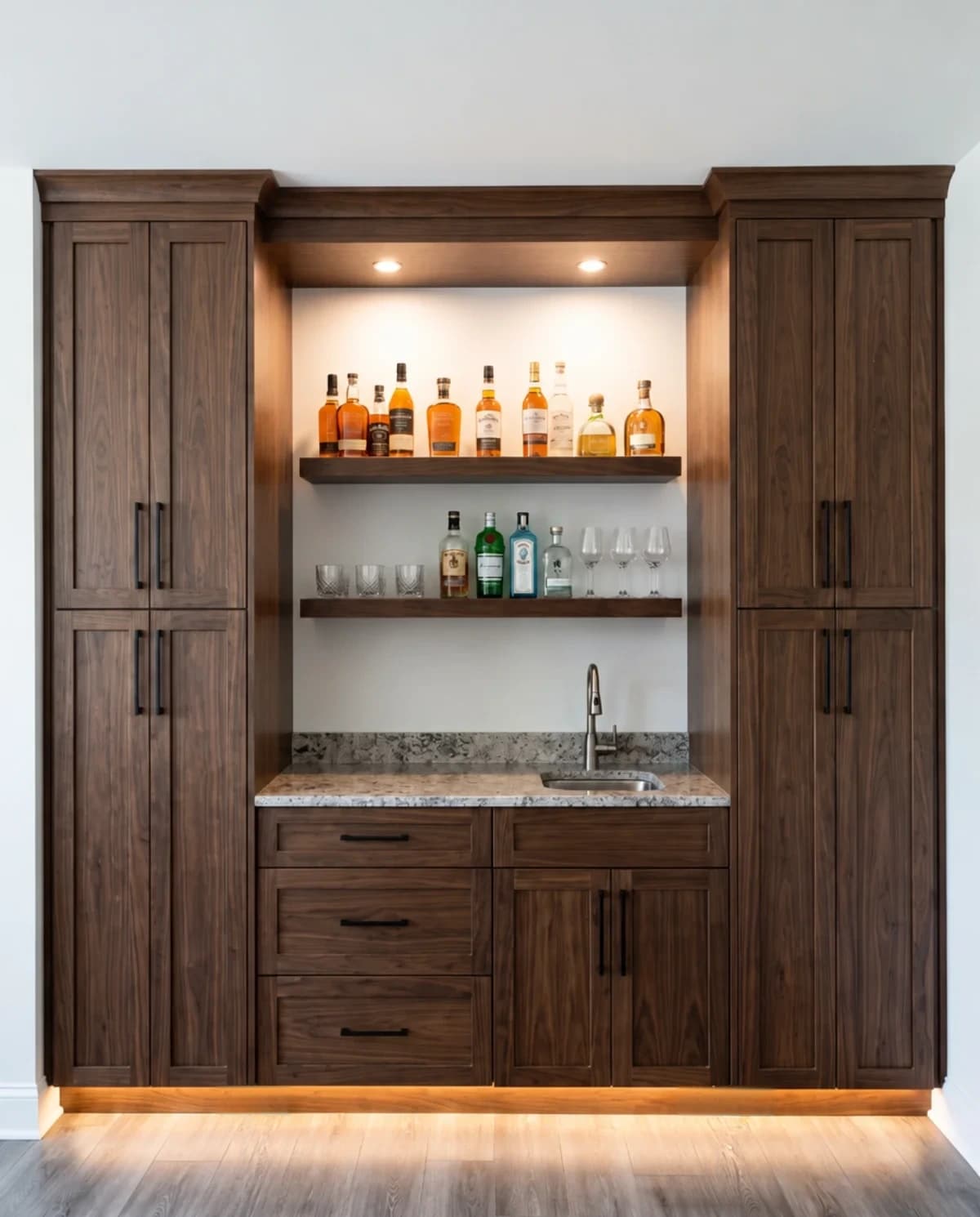 Walnut home bar with lit shelves of liquor bottles and glassware